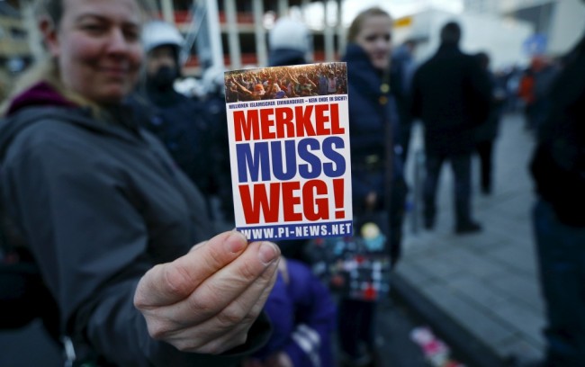 Сторонник движения против иммиграции и исламизации запада держит плакат с надписью "Меркель должна уйти" Фото REUTERS/Scanpix