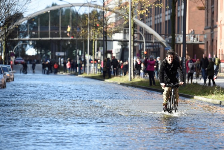 A cyclist rides through the HafenCity (Harbour City) district flooded during stormy weather caused by a storm called "Herwart," in Hamburg, Germany October 29, 2017. REUTERS/Fabian Bimmer