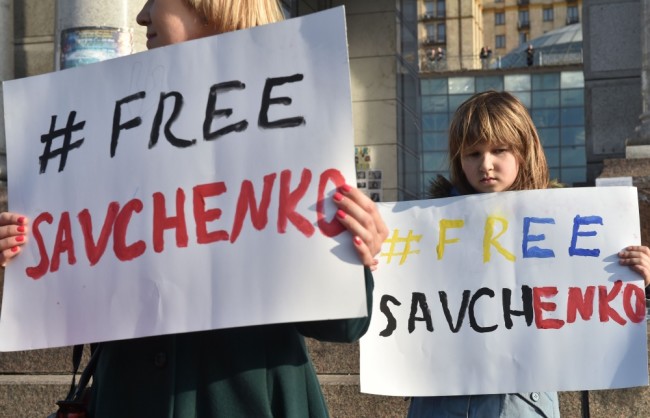 A girl and her mother hold placards reading "Free Savchenko" during a picket on Independence Square in Kiev on March 8, 2016, during a rally to support and demand the release from jail of the hunger-striking Ukrainian pilot Nadiya Savchenko.  Hundreds of angry Ukrainians picketed Moscow's embassy in Kiev as global calls grew for the release of a hunger-striking military helicopter pilot on trial in Russia. Nadia Savchenko is on trial for alleged involvement in the death of two Russian state television journalists in a mortar attack that occurred two months after Ukraine's pro-Moscow eastern revolt broke out in April 2014.  / AFP / SERGEI SUPINSKY