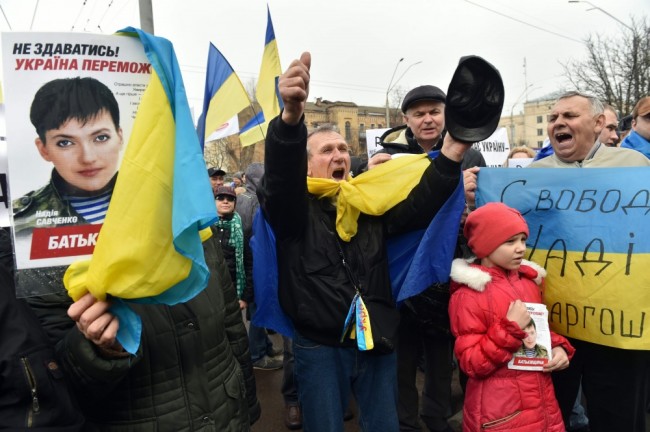 People shout slogan "Free Savchenko!" as they hold portraits of the jailed hunger-striking military helicopter pilot, during a rally in front of the Russian embassy in Kiev on March 9, 2016.  Ukraine today demanded that Moscow "immediately" free Nadiya Savchenko, a hunger-striking military helicopter pilot on trial in Russia. / AFP / SERGEI SUPINSKY