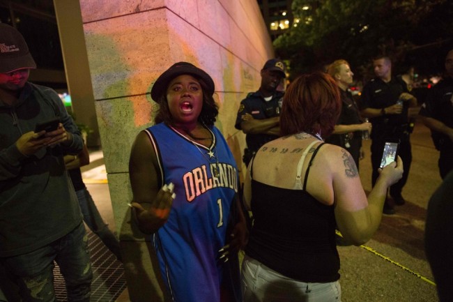 Protestors yell after police officers arrest a bystander following the shooting at a protest in Dallas on July 7, 2016. A fourth police officer was killed and two suspected snipers were in custody after a protest late Thursday against police brutality in Dallas, authorities said. One suspect had turned himself in and another who was in a shootout with SWAT officers was also in custody, the Dallas Police Department tweeted.  / AFP PHOTO / Laura Buckman