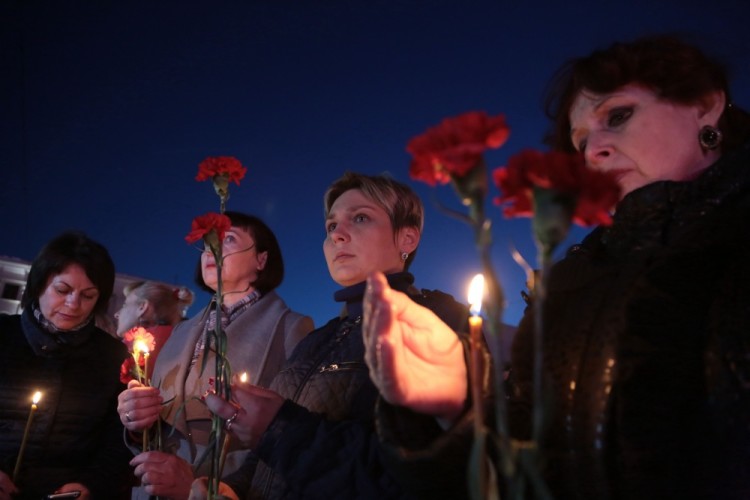 Women hold flowers and lit candles as they take part in a gathering in memory of victims of the blast in the Saint Petersburg metro in Simferopol, Crimea, on April 3, 2017. Ten people were killed and several more injured Monday after an explosion rocked the metro system in Russia's second city Saint Petersburg, and authorities launched a probe into suspected "act of terror". / AFP PHOTO / Max Vetrov