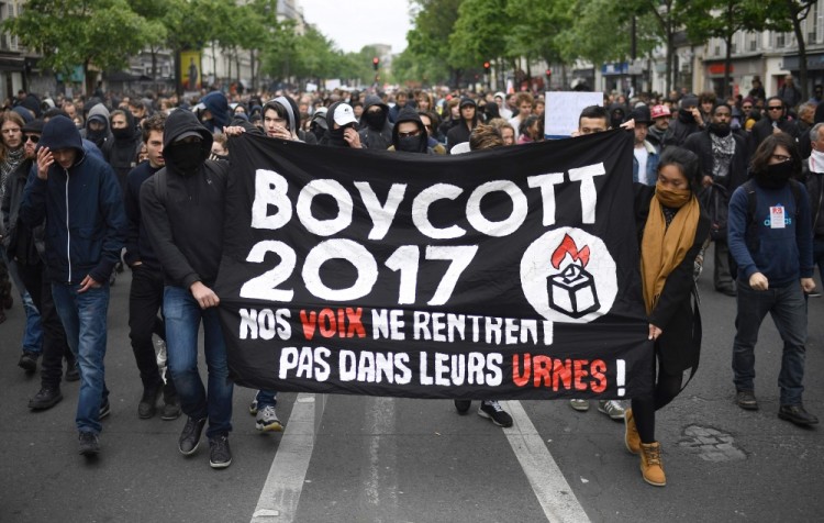 People hold a banner, reading "Boycott 2017, our votes do not enter their ballot boxes" during a demonstration called by the collectif "Front Social" and labour unions on May 8, 2017 a day after the French presidential election. / AFP PHOTO / Lionel BONAVENTURE