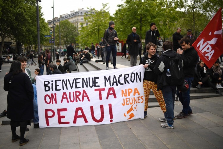 People hold a banner reading "Welcome Macron (president-elect Emmanuel Macron) we will get you" during a demonstration called by the collectif "Front Social" and labour unions on May 8, 2017 a day after the French presidential election. / AFP PHOTO / Lionel BONAVENTURE