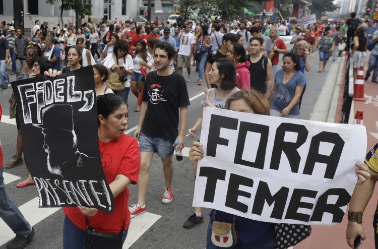 Demonstrators march with a sign that says in Portuguese "Get out Temer" and a drawing of Cuba's late President Fidel Castro, as they demand the impeachment of Brazil's President Michel Temer in Sao Paulo, Brazil, Sunday, Nov. 27, 2016. Protesters expressed outrage at a host of Temer's policies, including the government's proposal to cap spending to rein in the deficit. (AP Photo/Andre Penner)
