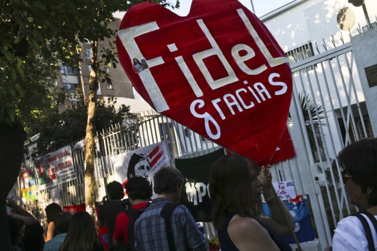 A woman holds a banner that reads in Spanish "Thanks Fidel" during a gathering to mourn the death of Cuba's leader Fidel Castro, outside the Cuban embassy in Santiago, Chile, Sunday, Nov. 27, 2016. Castro, who led a rebel army to improbable victory, embraced Soviet-style communism and defied the power of 10 U.S. presidents during his half century rule of Cuba, died Friday at age 90. (AP Photo/Esteban Felix)