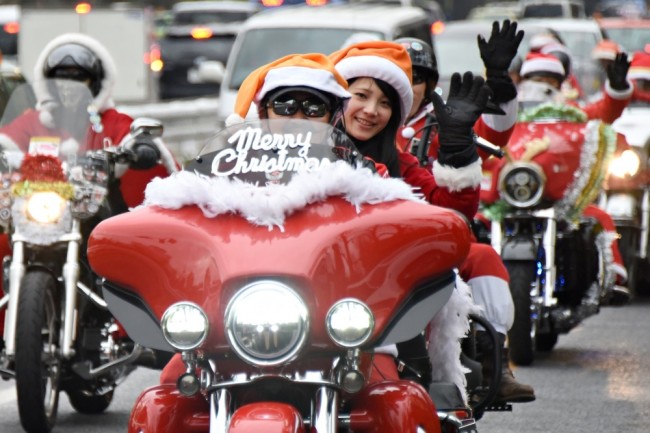 Motorcyclists dressed in Santa Claus outfits ride down the streets in downtown Tokyo during a Christmas "toy run" by the Harley Santa Club on December 23, 2015. Some 500 motorcyclists took part in the run on December 23 - a local holiday - to campaign against child abuse ahead of Christmas.     AFP PHOTO / Toru YAMANAKA