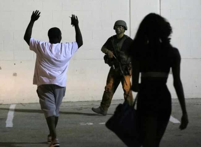 A man raises his hands as he walks near a law enforcement officer, following the shootings Thursday of several police officers in downtown Dallas, early Friday, July 8, 2016. (AP Photo/LM Otero)