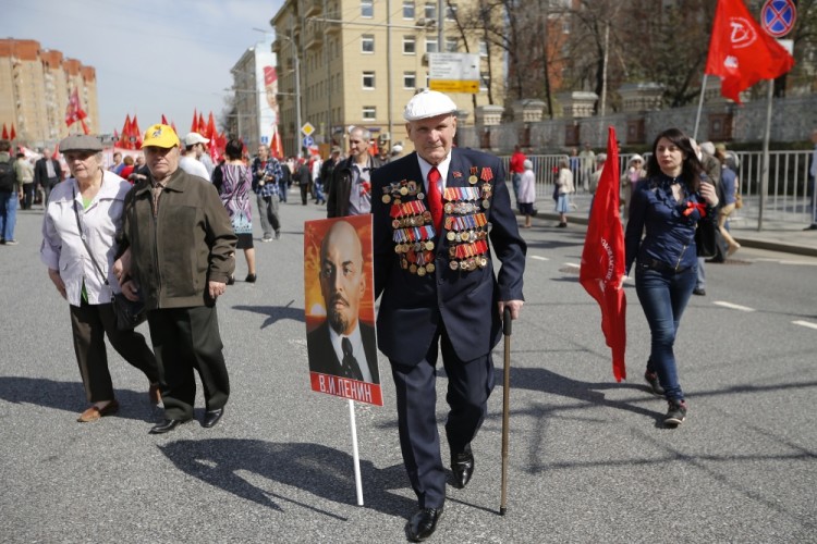 A man wearing a jacket with many medals walks with a portrait of Soviet founder Vladimir Lenin during a Communist rally to mark May Day in Moscow, Russia, Monday, May 1, 2017. As in Soviet times, people paraded across Moscow with the red flags with Communist hammer and sickle. (AP Photo/Alexander Zemlianichenko)