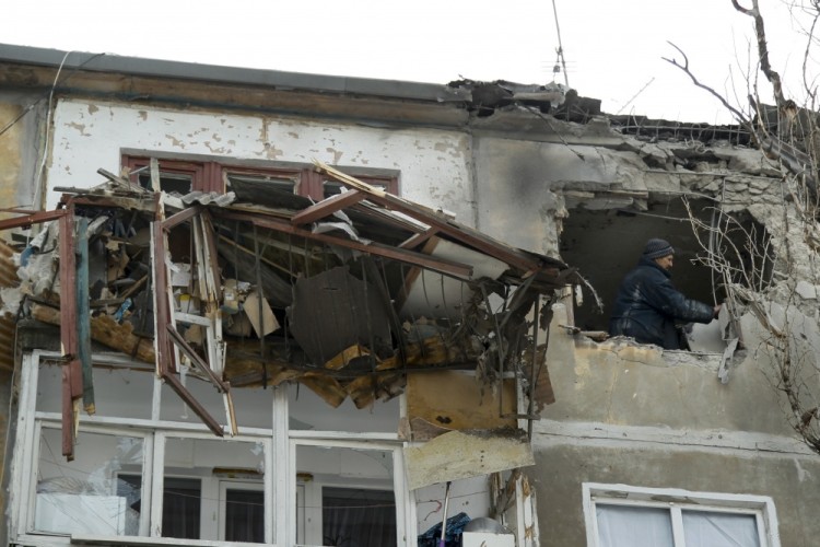 A municipal worker inspects damage to a home after shelling in the city of Donetsk, eastern Ukraine, Wednesday, Feb. 1, 2017. Heavy fighting between government troops and Russia-backed rebels continues in eastern Ukraine on Wednesday, at least 10 people have been killed since Monday and dozens wounded. (AP Photo/Alexander Ermochenko)