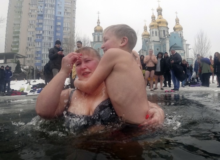 Orthodox believers, a mother and son, cross themselves as they plunge into icy water during the celebration of Epiphany in Kiev, Ukraine, Thursday, Jan. 19, 2017. Thousands of Orthodox believers celebrate the holiday of the Epiphany on Jan. 19, and traditionally plunge into holes cut through thick ice on rivers and ponds to cleanse themselves with water deemed holy for the day. (AP Photo/Efrem Lukatsky)