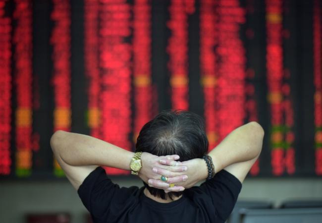Инвестор, наблюдающий за изменениями котировок на табло. Фото AFP/Scanpix