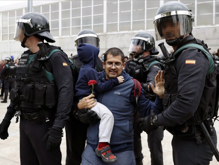 epa06237486 Spanish National riot policemen evict a Catalan man carrying child in his arms during clashes outside the Ramon Llull school during the '1-O Referendum' in Barcelona, Catalonia, on 01 October 2017. National Police officers and Civil guards have been deployed in Barcelona to prevent the people from entering to the polling centers and vote in the Catalan independence referendum, that has been banned by the Spanish Constitutional Court. The police action has provocked clashes between pro-independence people and the police forces.  EPA/Andreu Dalmau ATTENTION EDITORS: POLICEMAN'S FACE AND CHILD'S FACE BLURED DUE TO SPANISH LAW