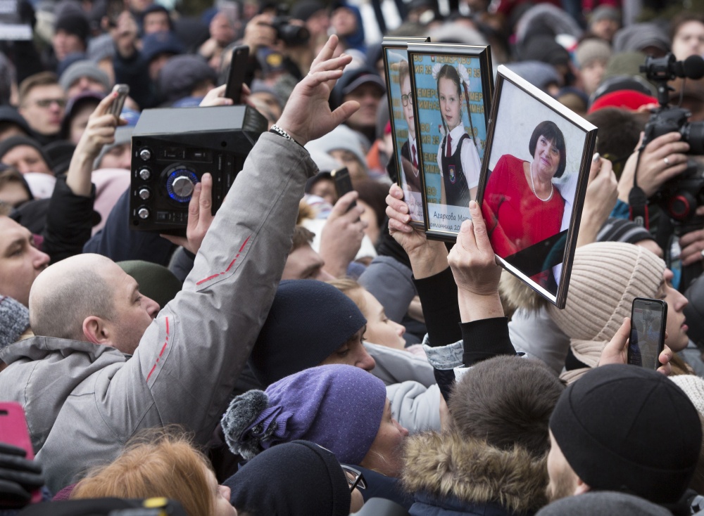 Участник митинга показывают портреты близких, которых они потеряли во время пожара. Фото AP Photo/Scanpix/LETA