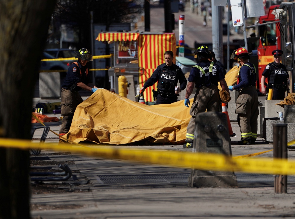 Сотрудники экстренных служб накрывают тело погибшего в результате наезда микроавтобуса на пешеходов в Торонто. Фото Reuters/Scanpix/LETA
