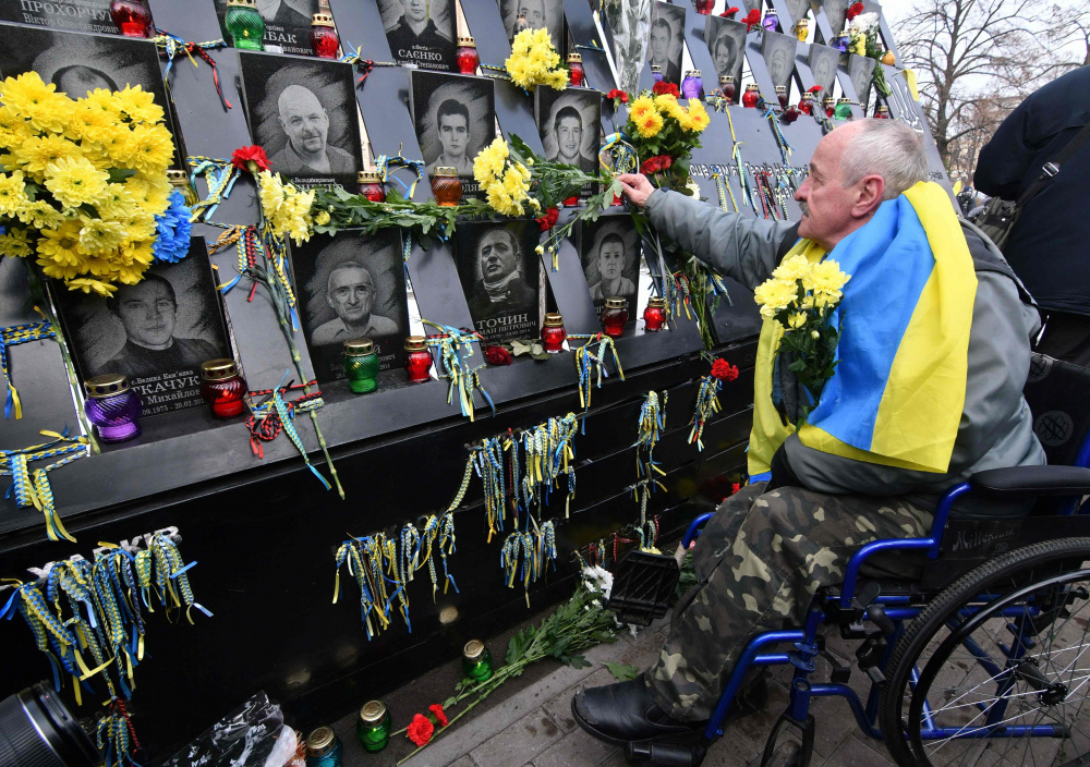 Мужчина возлагает цветы к мемориалу убитых активистов Майдана, Киев, 21 ноября 2018 года. Фото AFP/Scanpix/LETA