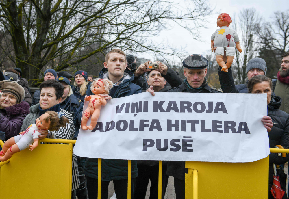Одетые в полосатые робы узников концлагерей они стояли с плакатами «Они сражались за Адольфа Гитлера». Фото AFP/Scanpix/Leta