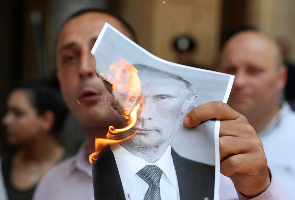 Один из протестующих сжег портрет президента России Владимира Путина. Фото REUTERS/Scanpix/Leta