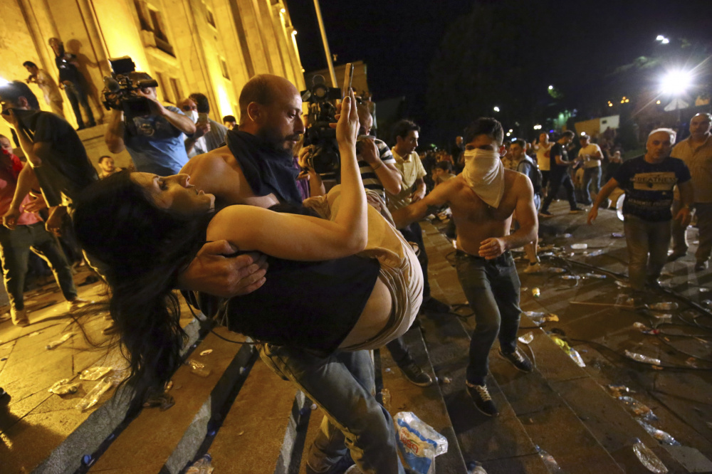 Протестующие выносят пострадавших в столкновениях с полицией. Фото AP/Scanpix/Leta