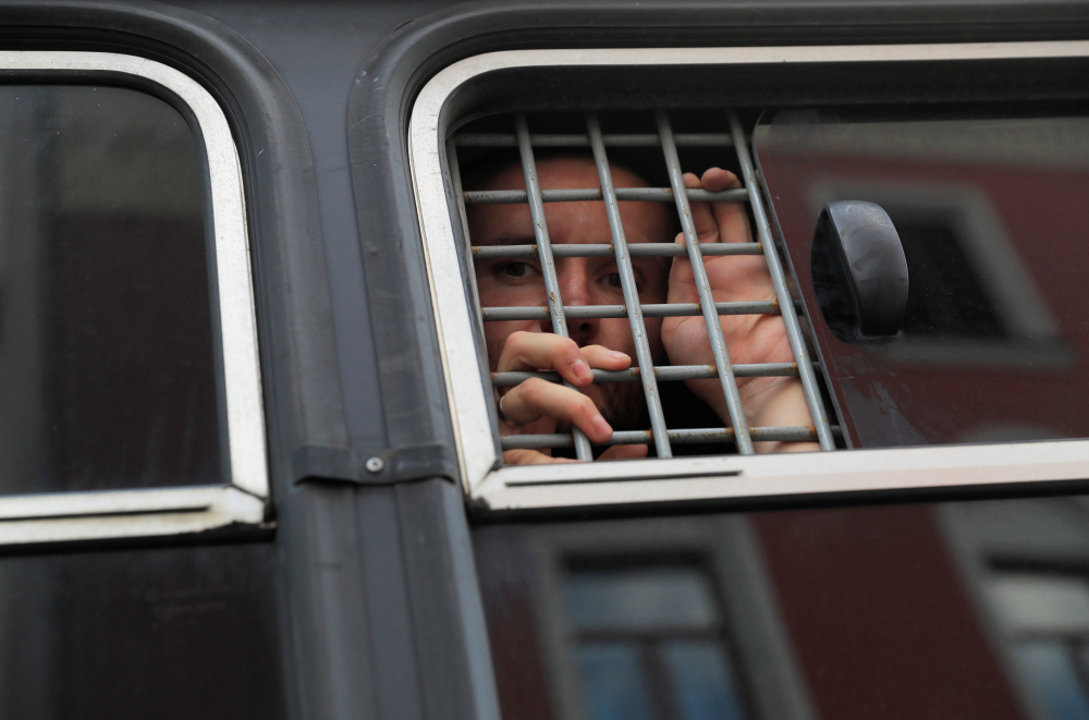 Задержанные в автозаке напротив отражающегося в стекле здания мэрии Москвы. Фото  REUTERS/Scanpix/Leta