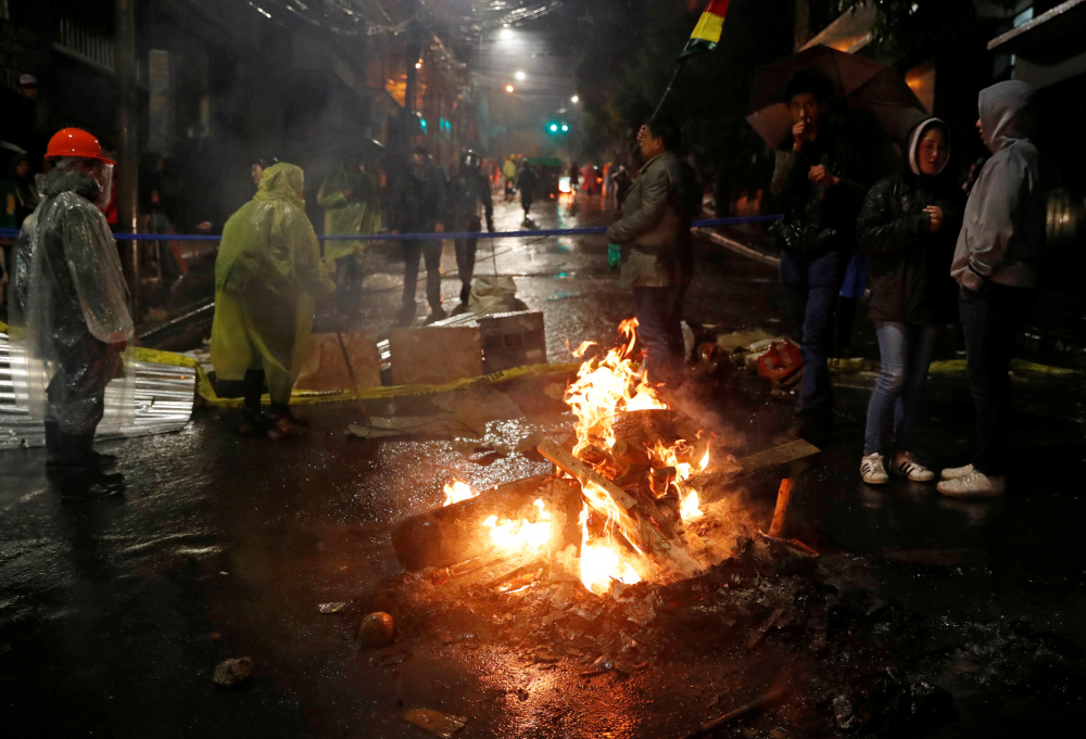Демонстранты стоят возле горящей баррикады во время акции протеста. Фото: CARLOS GARCIA RAWLINS / TASS / Scanpix / Leta