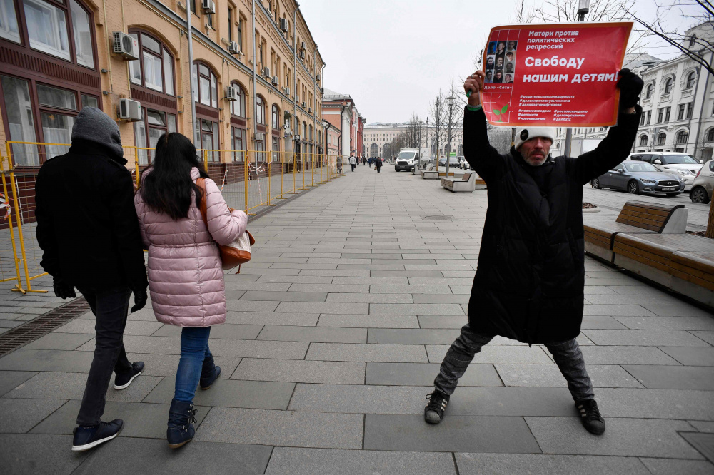 Мужчина держит плакат в поддержку политзаключенных. Фото: ALEXANDER NEMENOV / TASS / Scanpix / Leta