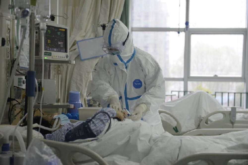 Сотрудник центрального госпиталя в Ухани около пациента. Фото: via REUTERS / TASS / Scanpix / Leta