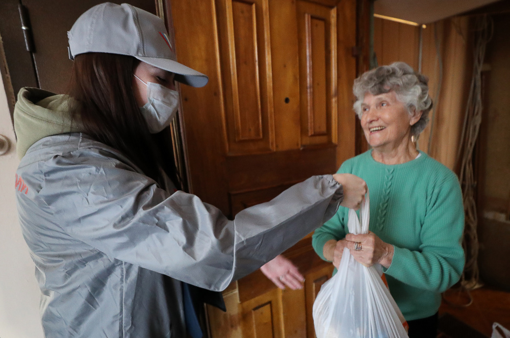 Волонтер приносит еду пожилой женщине в карантине. Фото: Alexander Demianchuk / TASS / Scanpix / Leta