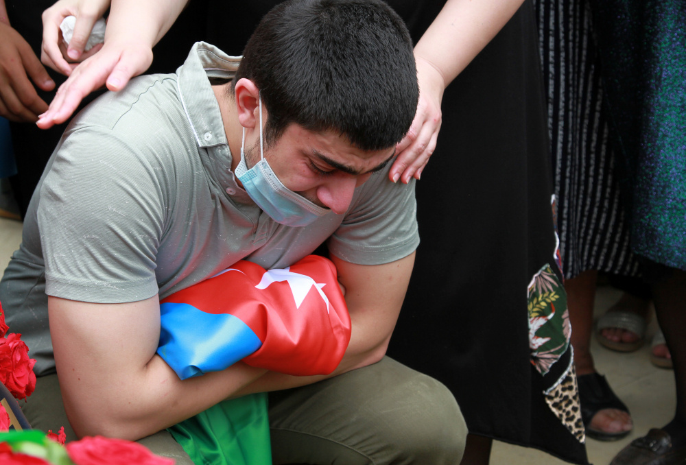 Гражданин Азербайджана скорбит с национальным флагом на похоронах полковника Ильгара Мирзоева, погибшего в столкновениях на границе с Арменией. Фото REUTERS/Scanpix/Leta