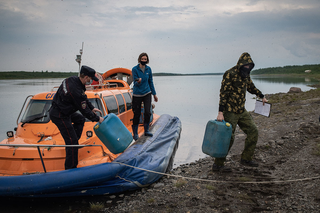 Полицейские уносят топливо с нашей лодки. Фото Юрия Козырева / «Новая газета»