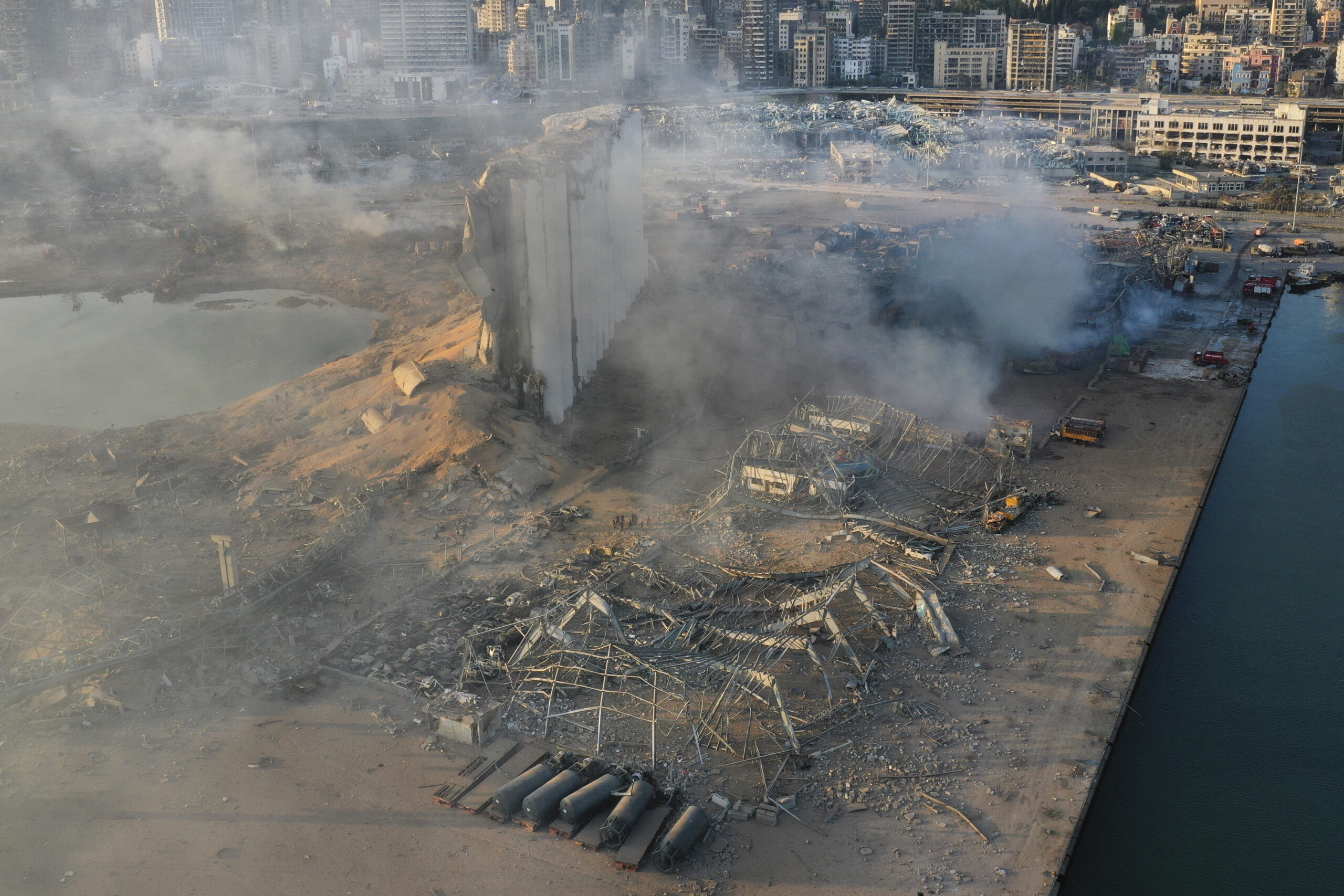 На утро после взрыва все еще продолжают тлеть небольшие огни на месте происшествия. Фото Вертолет пытается потушить пламя в порту Бейрута. Фото AP Photo/Hussein Malla/Scanpix/Leta