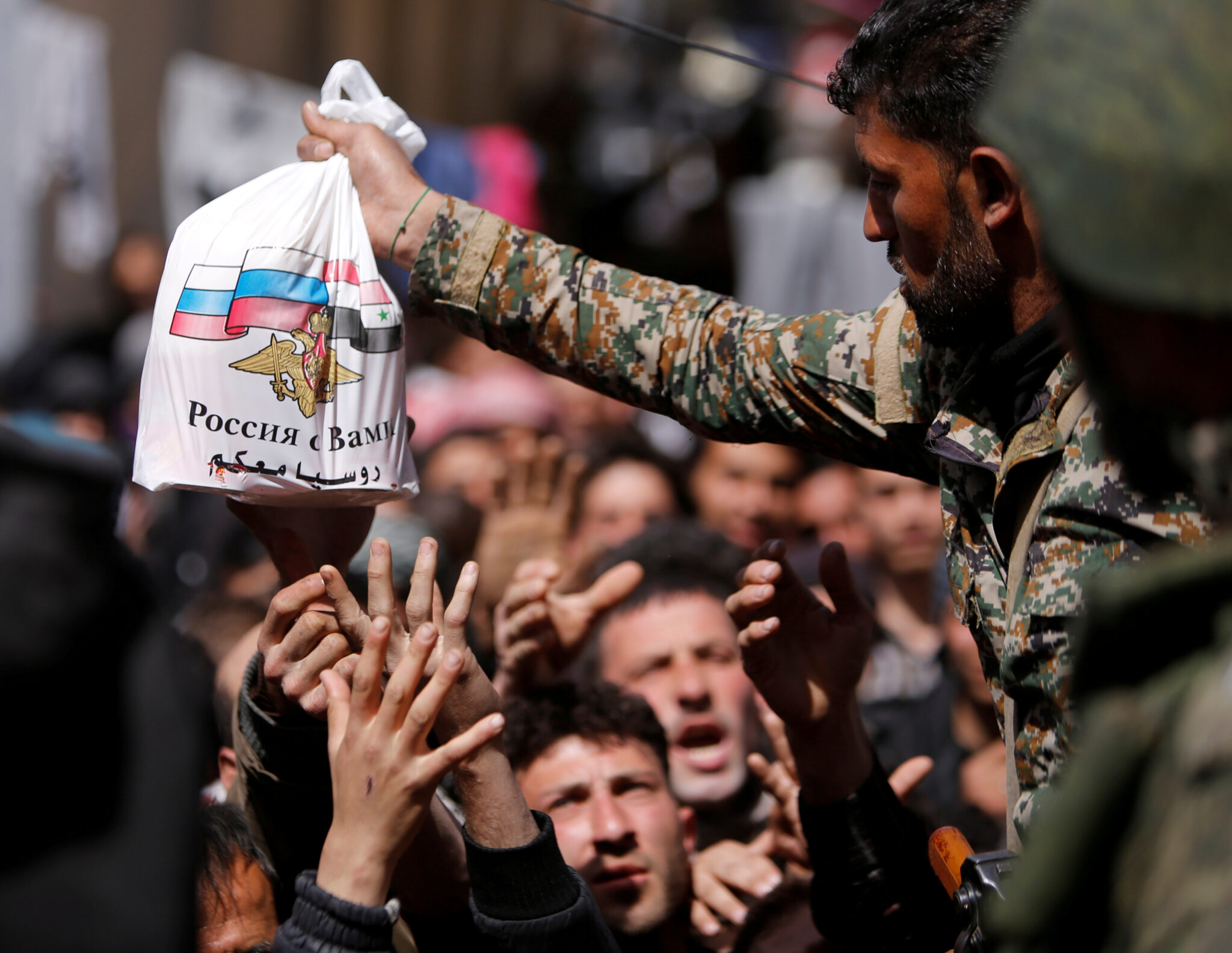 Солдат сирийской армии раздает помощь российских войск мирным жителям в Сирии. Фото OMAR SANADIKI / TASS / Scanpix / Leta
