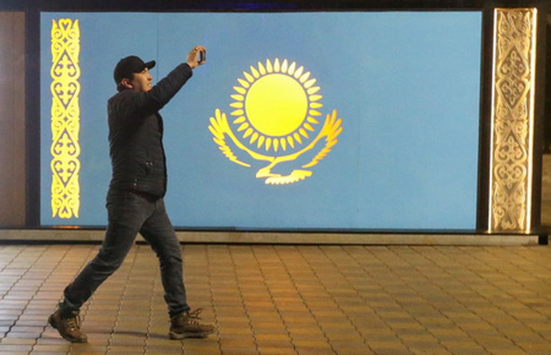 Участник протеста на фоне флага Казахстана. Фото Pavel Mikheyev/Reuters/Scanpix/LETA