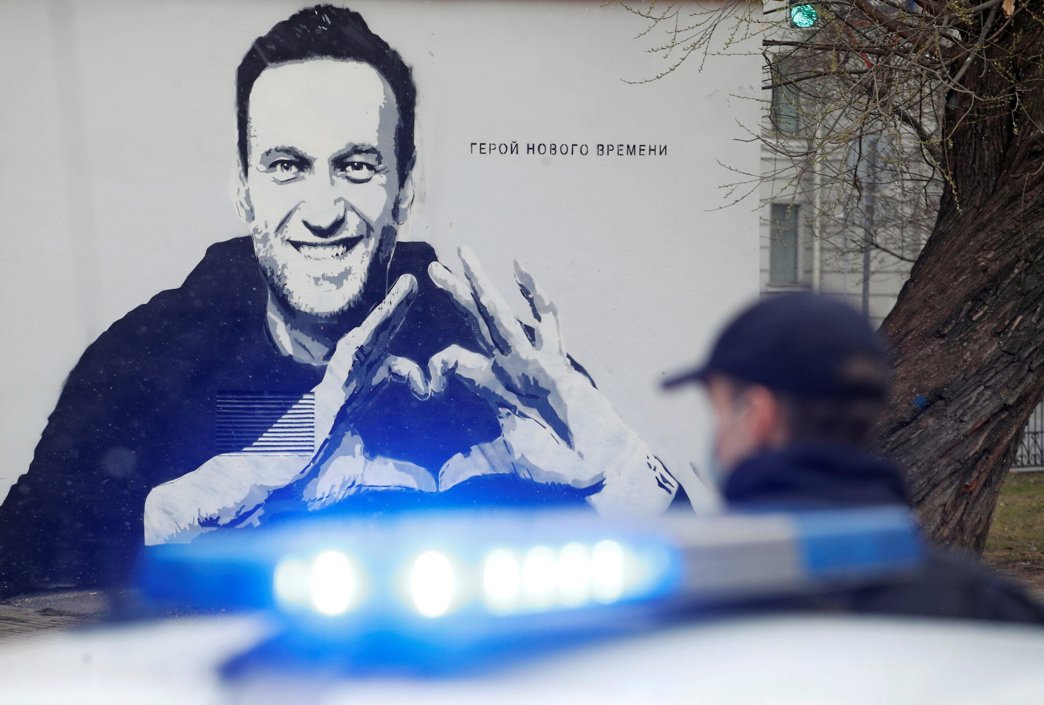 Полицейский стоит рядом с автомобилем перед граффити с изображением заключенного в тюрьму российского оппозиционного политика Алексея Навального в Санкт-Петербурге. 28 апреля 2021 года. Фото Anton Vaganov/REUTERS/Scanpix/Leta