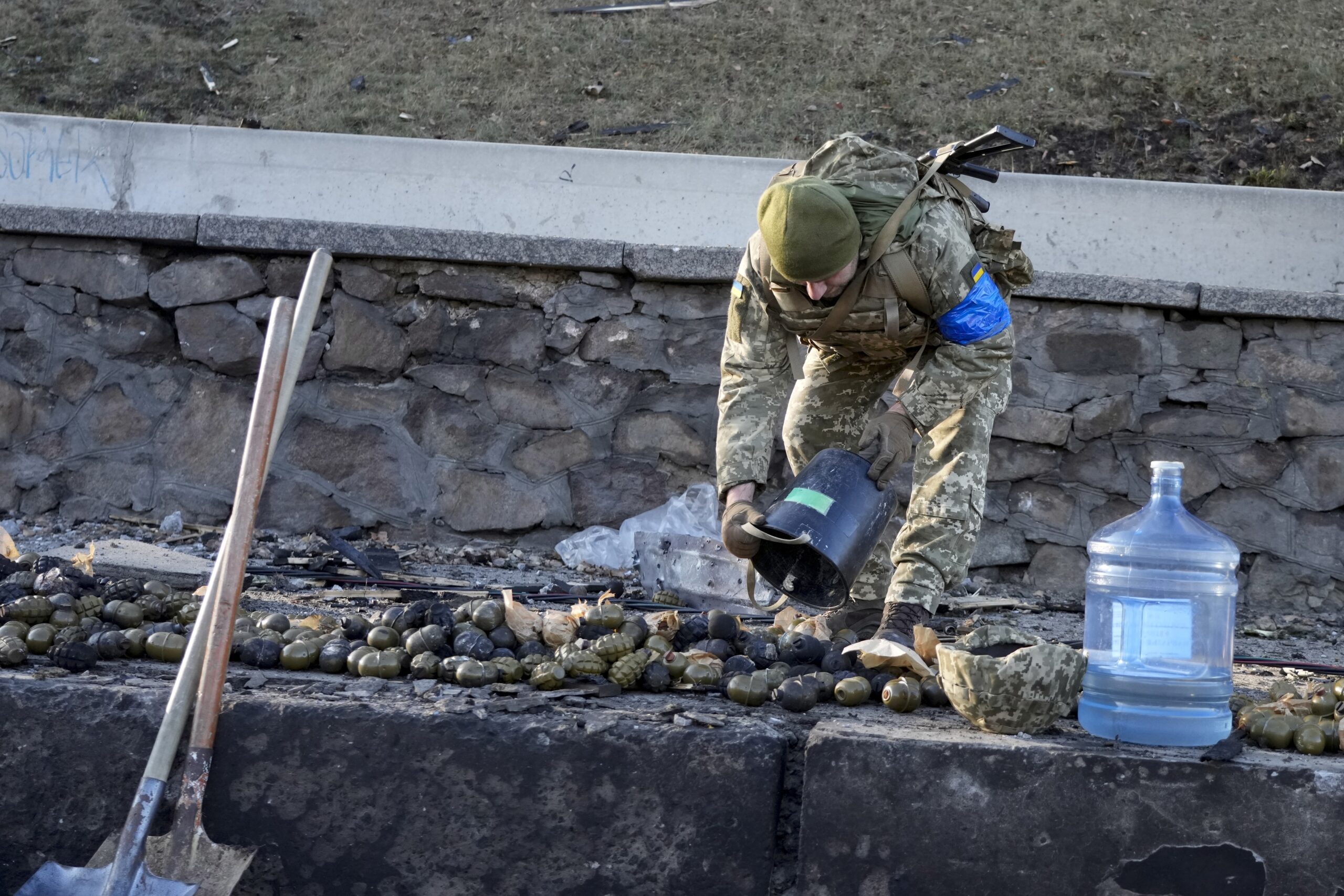 Украинский солдат собирает гранаты возле горящих военных грузовиков на улице в Киеве. Украина. 26 февраля 2022 года. Фото Efrem Lukatsky/AP Photo/Scanpix/Leta