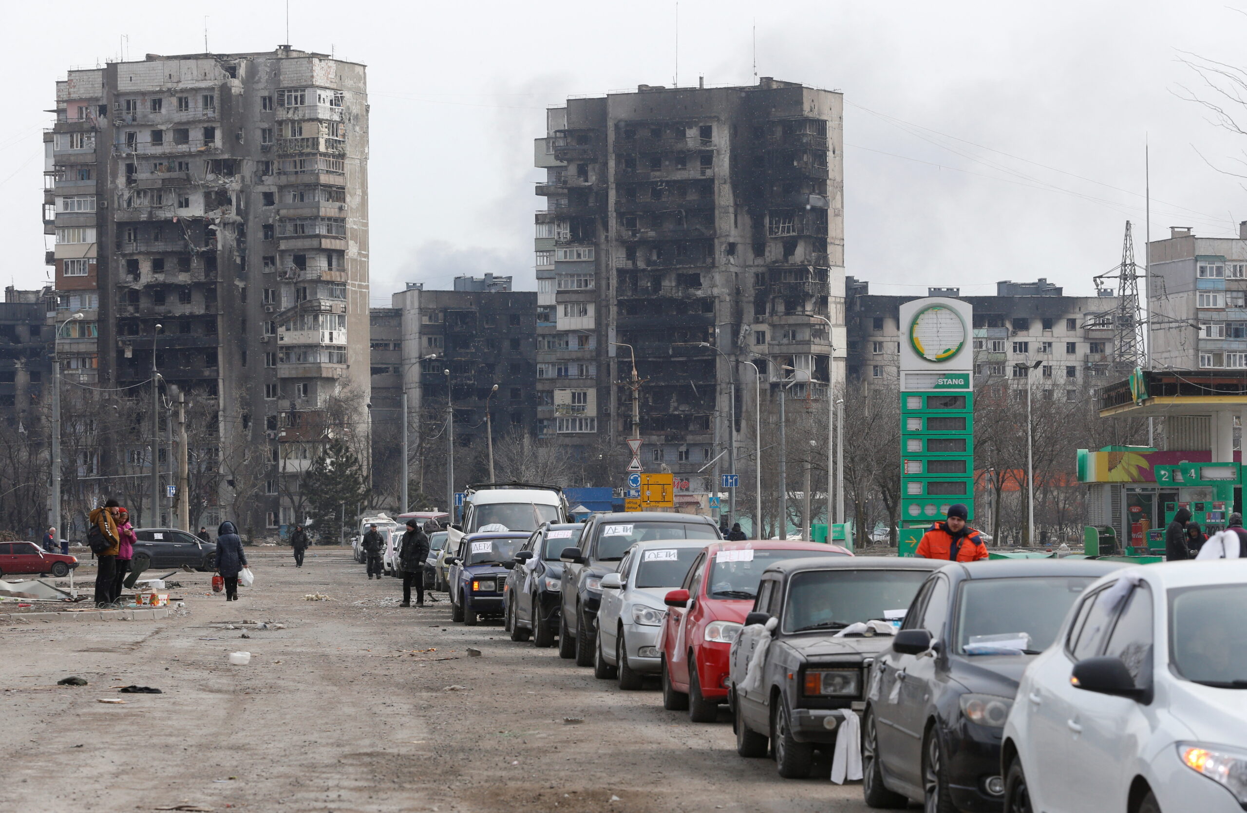 Вереницв автомобилей возле многоквартирных домов, разрушенных во время обстреров, покидающих город. Мариуполь, Украина, 17 марта 2022 года. © REUTERS / Alexander Ermochenko / Scanpix / Leta