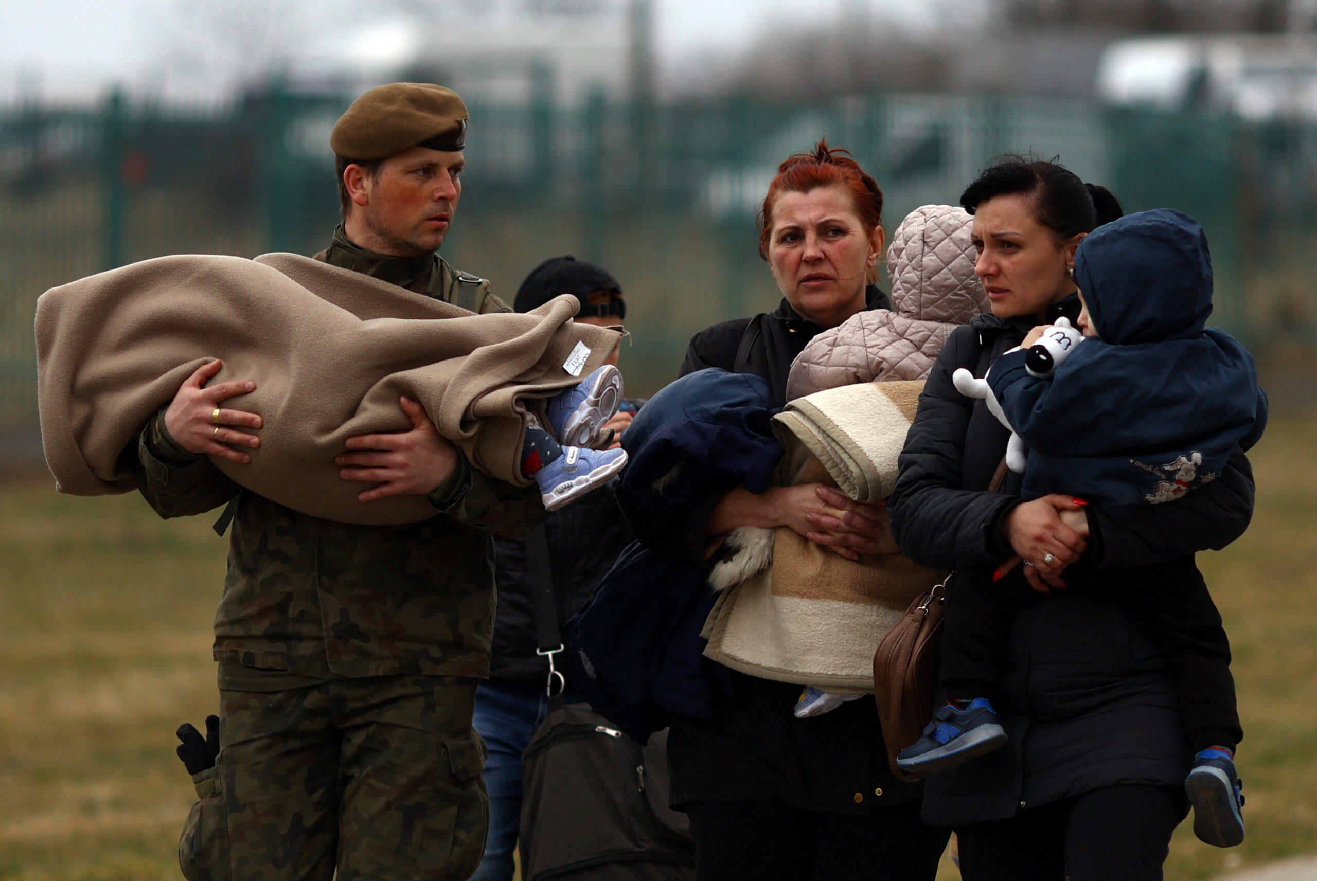 Польский солдат несет ребенка при пересечении границы украинскими беженцами в Медыке. Польша. 26 марта 2022 года. Фото Hannah McKay/REUTERS/Scanpix/LETA
