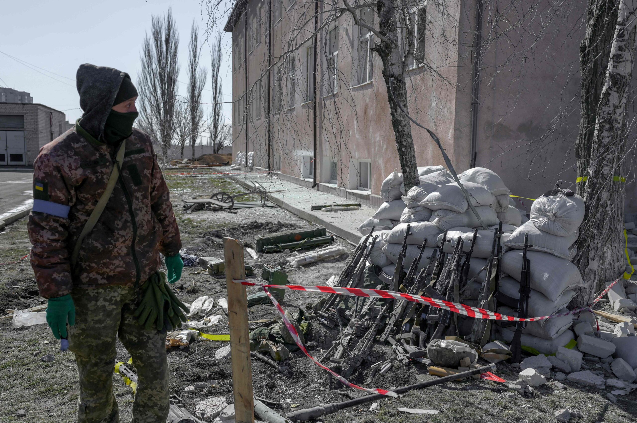 Украинский военный рядом с ружьями раненых или погибших в Николаеве солдат. 19 марта 2022 года. Фото BULENT KILIC/AFP/Scanpix/Leta