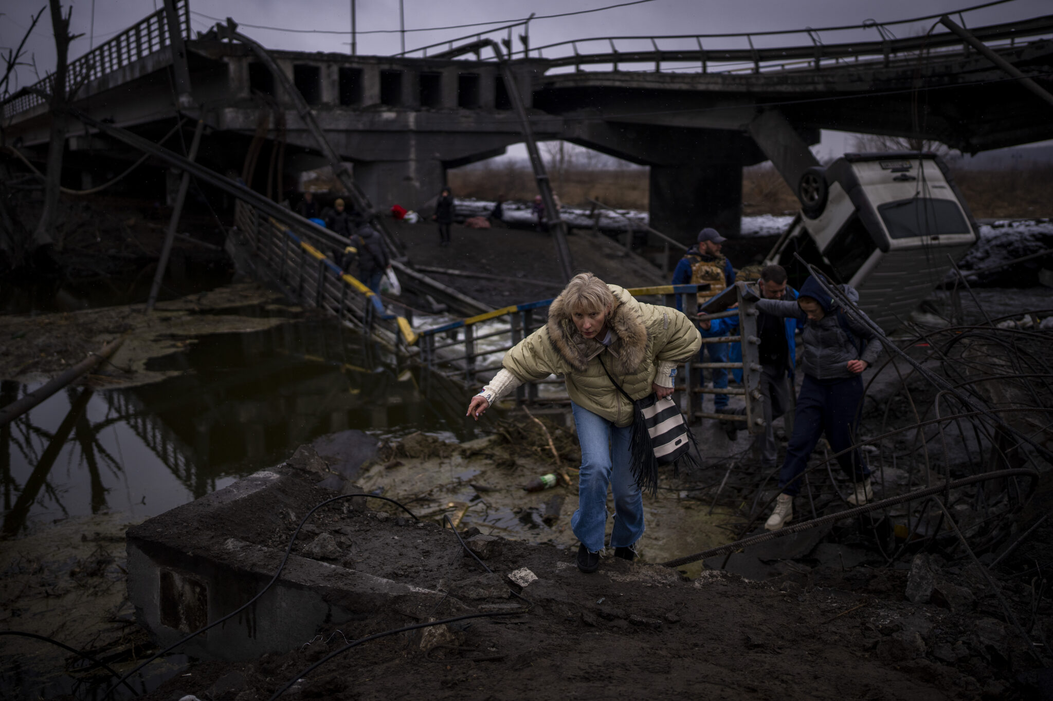 Женщина бежит со своей семьей по разрушенному мосту на окраине Киева, Украина. 2 марта 2022 года. Фото Emilio Morenatti/AP Photo/Scanpix/Leta 