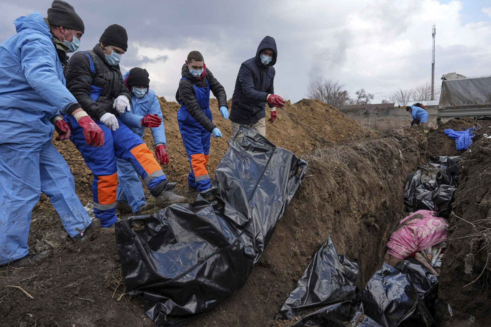 Люди кладут тела погибших в братскую могилу на окраине Мариуполя, поскольку не могут похоронить своих близких из-за сильных обстрелов российскими войсками. Фото Evgeniy Maloletka/AP Photo/Scanpix/Leta