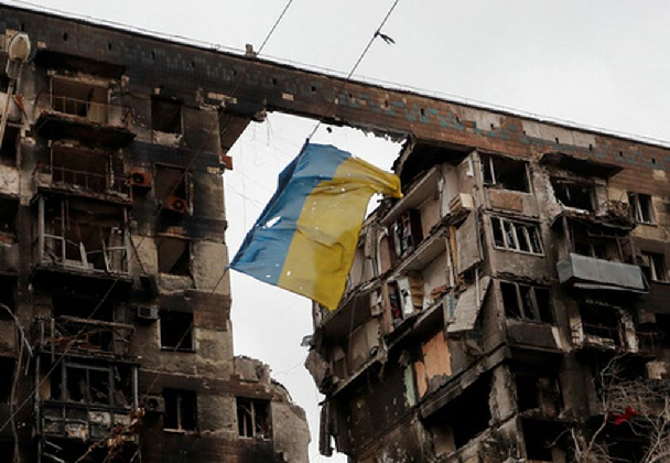 Украинский флаг на фоне разрушенного здания в Мариуполе. Фото REUTERS/Alexander Ermochenko/File Photo/Scanpix/LETA