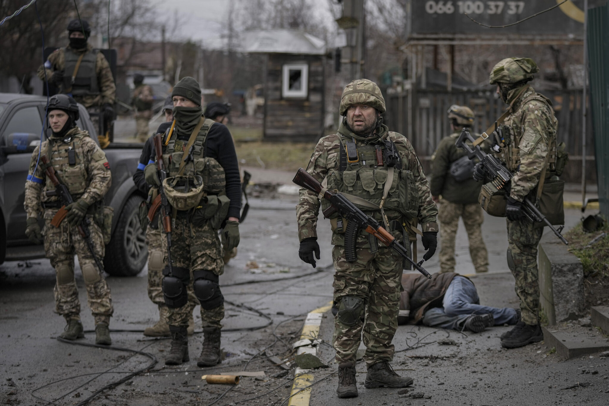 Украинские военнослужащие стоят рядом с телом мужчины в гражданской одежде. город Буча. 2 апреля 2022 года. Фото Vadim Ghirda/AP Photo/Scanpix/LETA