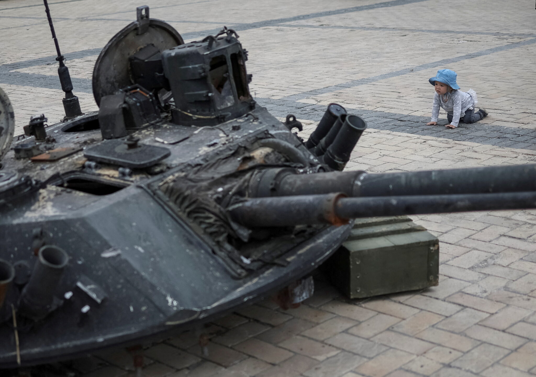Ребенок рядом с уничтоженной российской бронетехникой на Михайловской площади в центре Киева. 21 мая 2022 года. REUTERS/Gleb Garanich/Scanpix/LETA