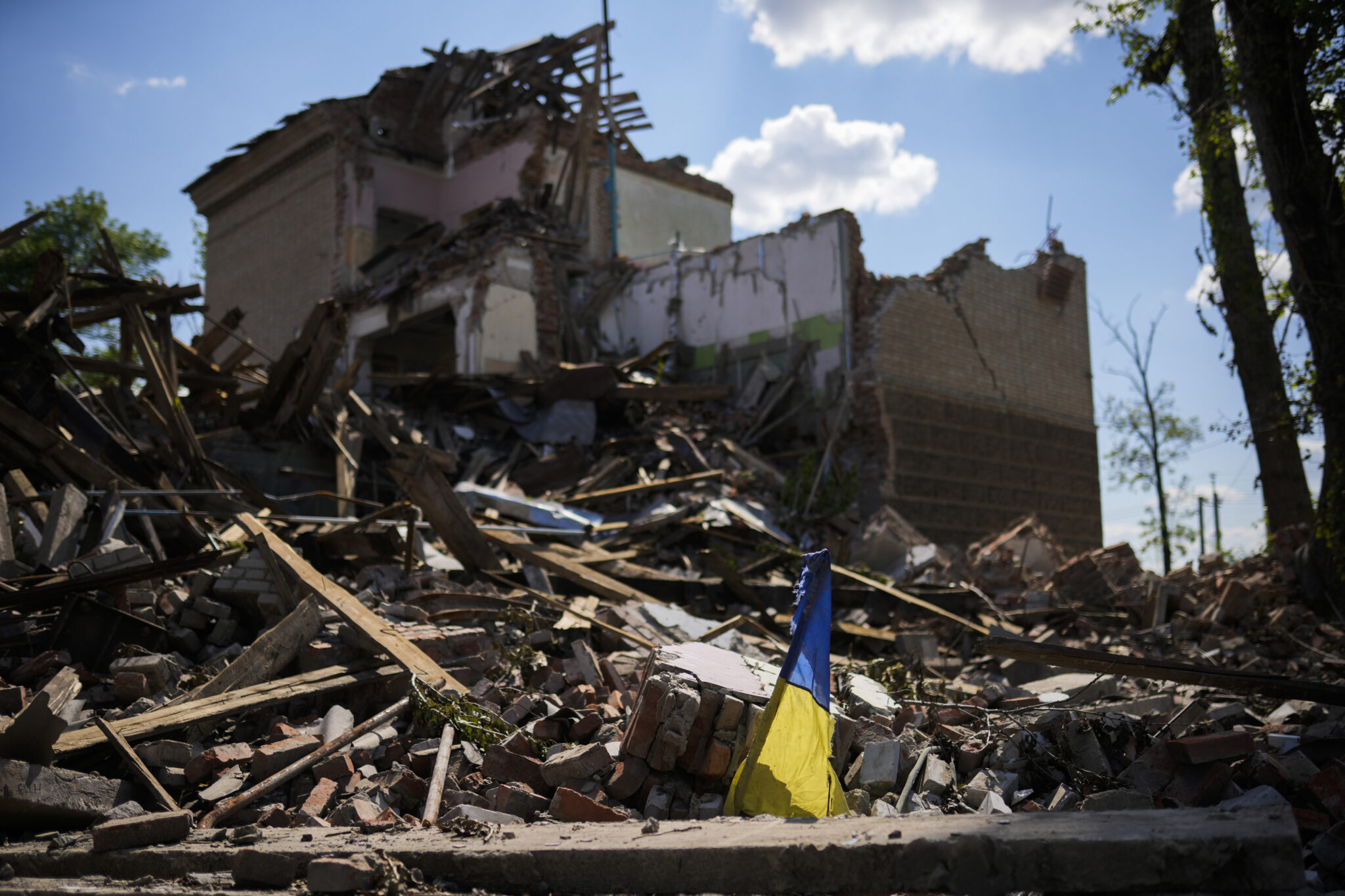 Украинский флаг на развалинах школы, разрушенной в результате российской бомбардировки. Бахмут. 24 мая 2022 года. Фото AP Photo/Francisco Seco/Scanpix/LETA