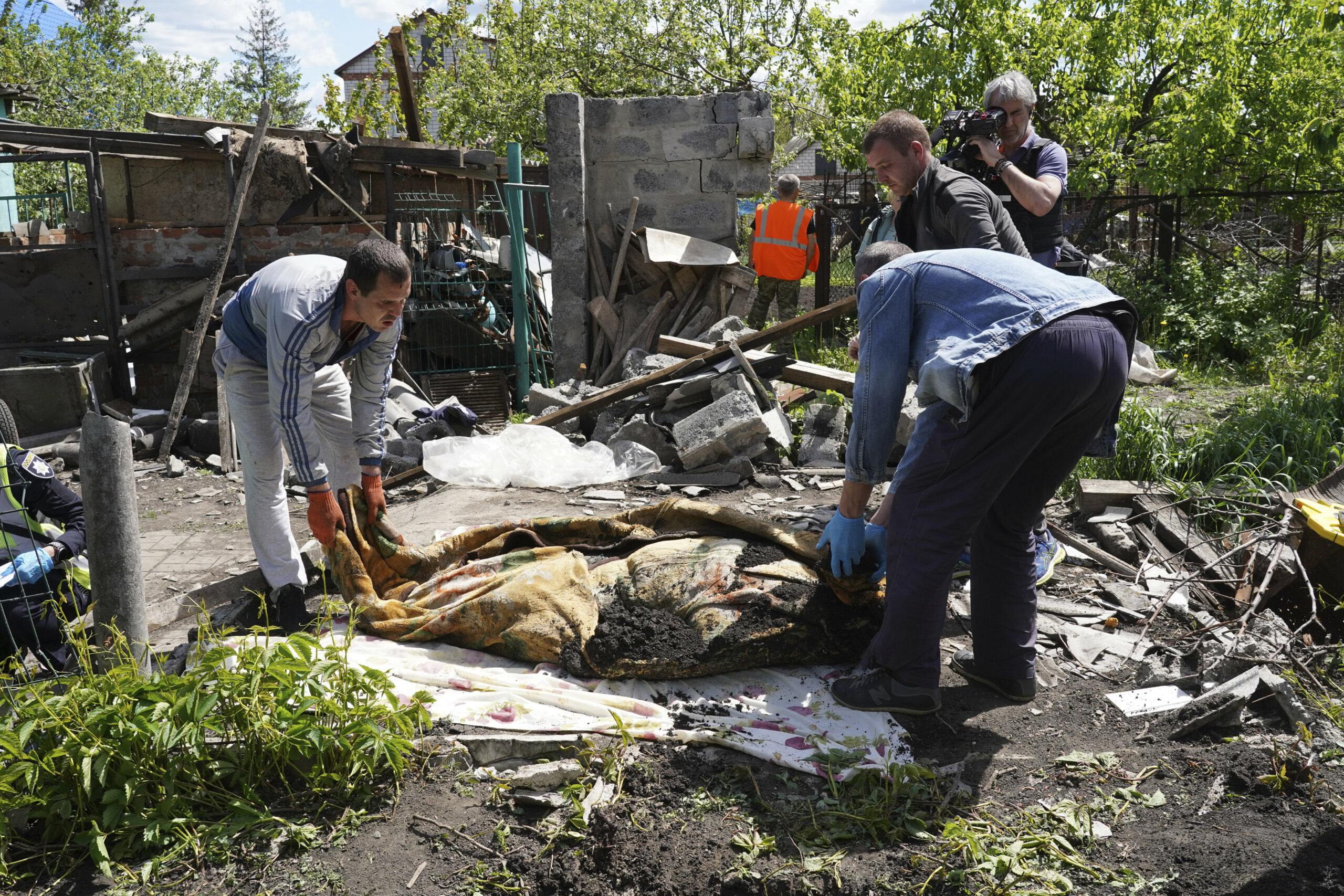 Полиция и волонтеры эксгумируют тело мирного жителя, погибшего в результате российского обстрела в селе Малая Рогань на окраине Харькова. 16 мая 2022 года. Фото AP Photo/Andrii Marienko/Scanpix/LETA