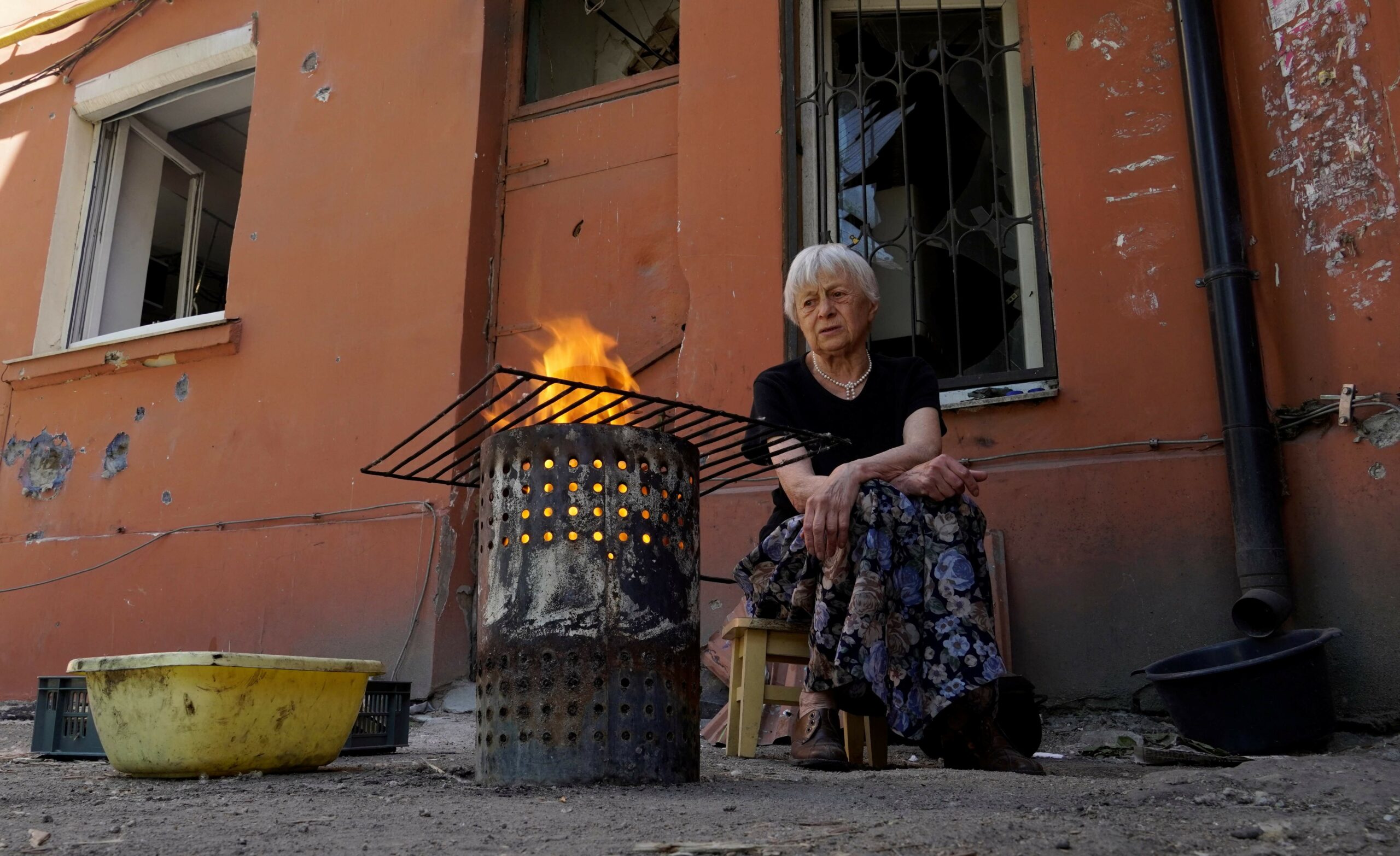 Женщина готовит пищу во дворе в Мариуполе. Фото STRINGER/AFP/Scanpix/LETA