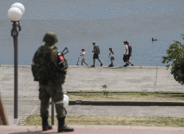 Российский солдат смотрит на мирных жителей в Херсоне. Фото SERGEI ILNITSKY/EPA/Scanpix/LETA
