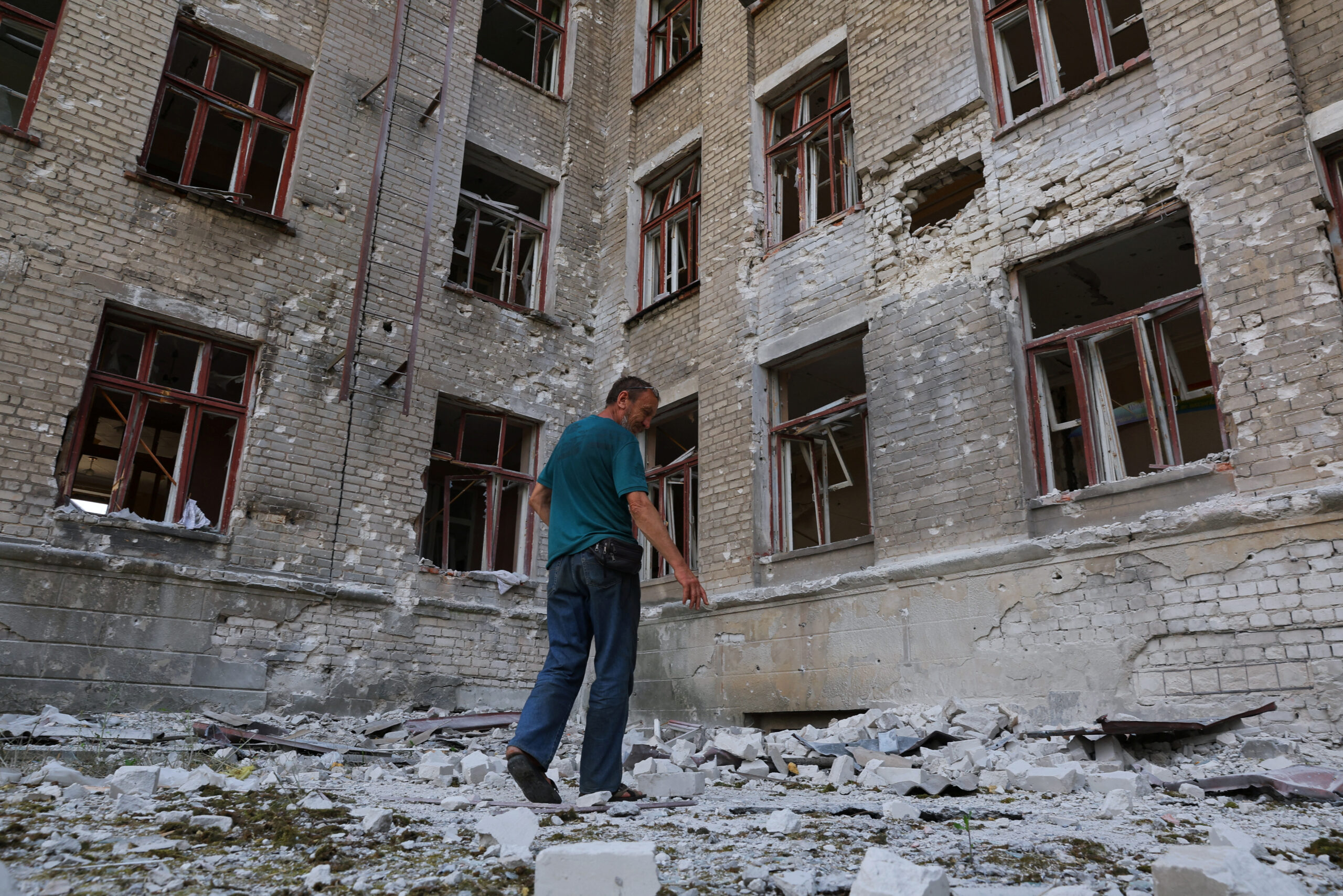 Местный житель Андрей Бутенко на фоне разрушенной школы в Лисичанске. 5 июля 2022 года. Фото REUTERS/Alexander Ermochenko/Scanpix/LETA