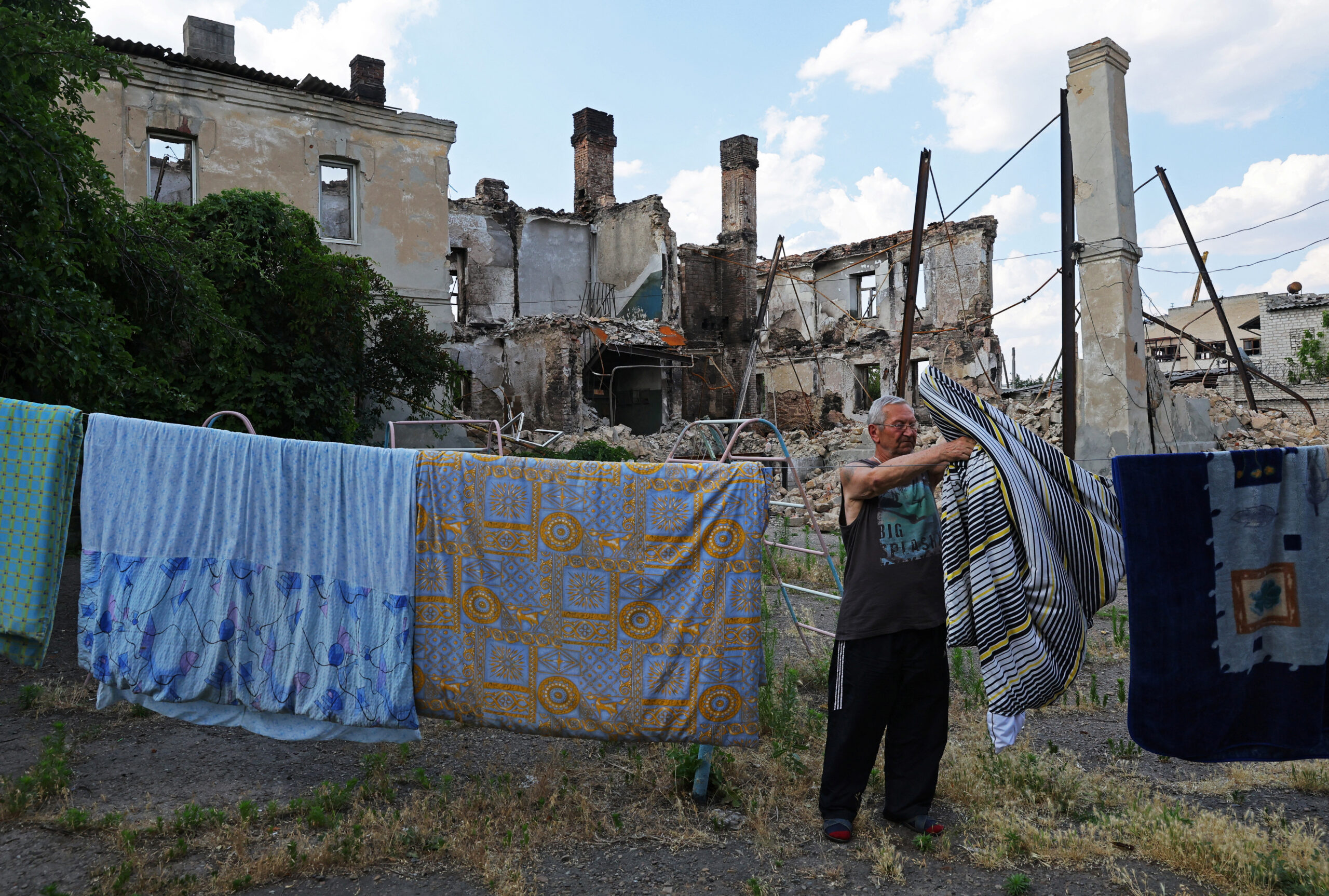 65-летний местный житель Сергей развешивает белье рядом с руинами домов в Лисичанске. 5 июля 2022 года. Фото REUTERS/Alexander Ermochenko/Scanpix/LETA