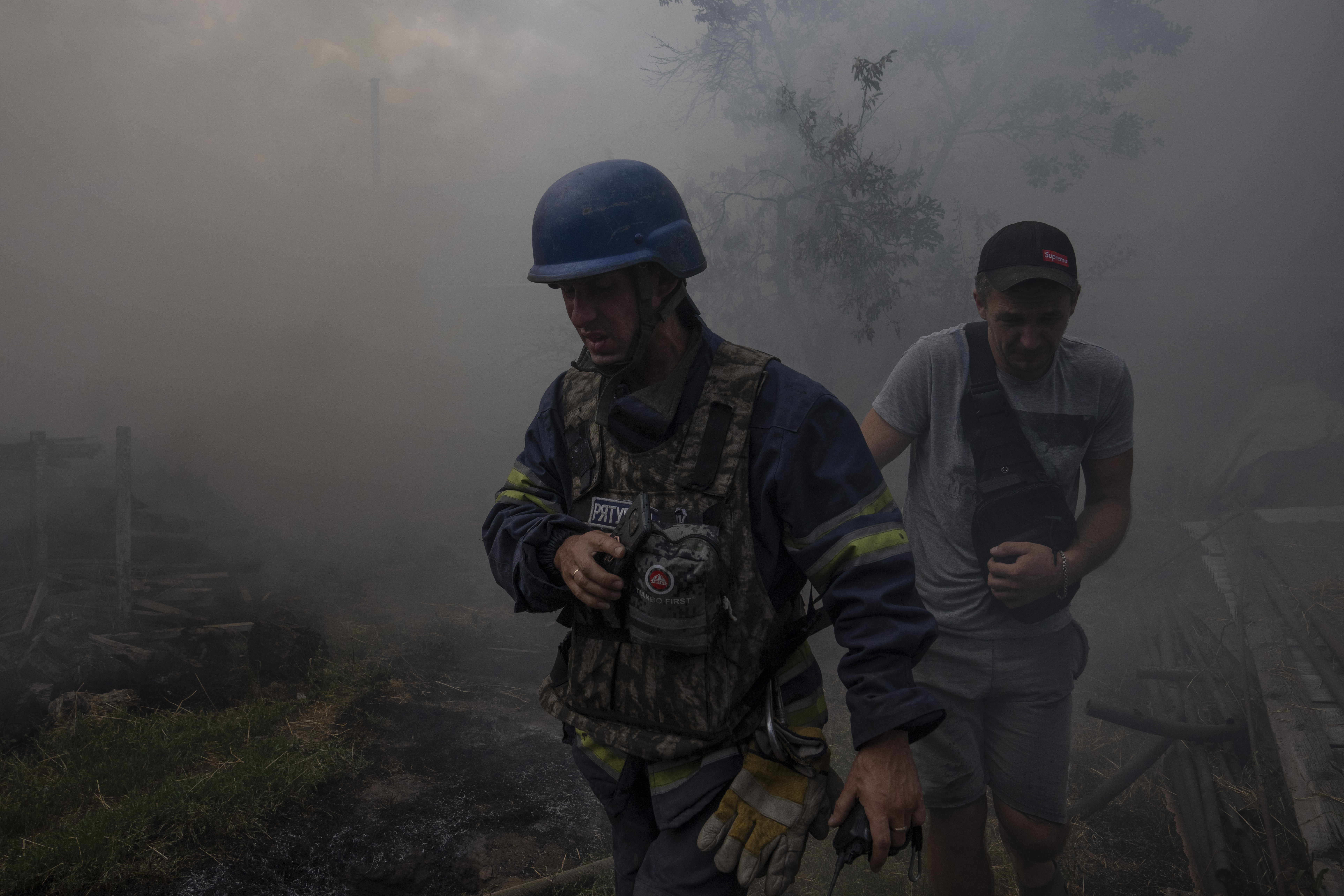 Пожарный с местным жителям возле горящего дома. Константиновка. 9 июля 2022 года. Фото AP Photo/Nariman El-Mofty/Scanpix/LETA